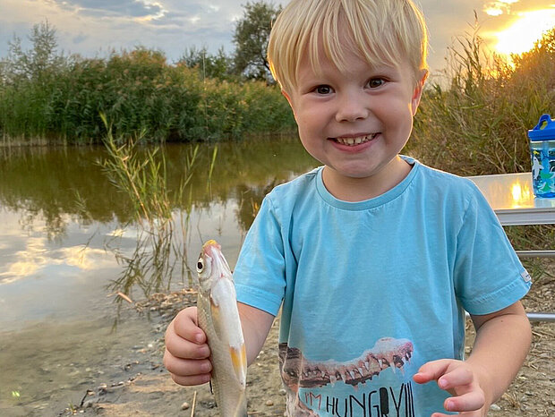 Kleiner Junge mit gefangenem Fisch in der Hand